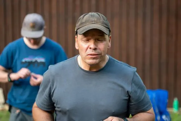 Mann mit geschlossenen Augen hält einen Gegenstand in der Hand