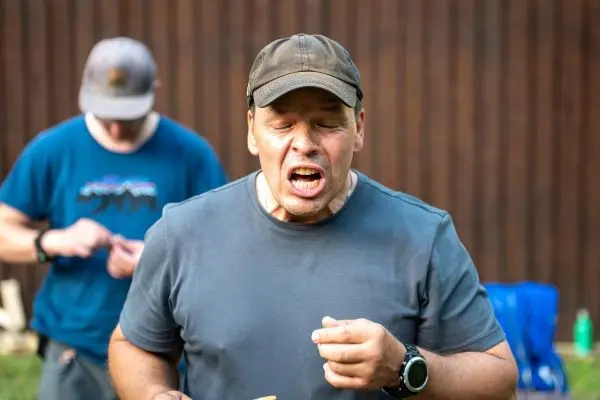 Mann mit Mütze hält etwas in der Hand und spricht laut