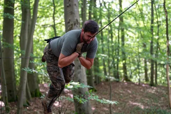 Mann nutzt Seil zur Querung zwischen Bäumen im Wald