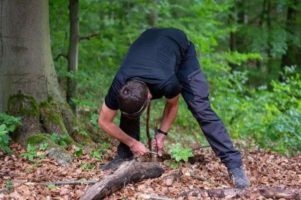 Messer bearbeitet Holzstück auf dem Waldboden