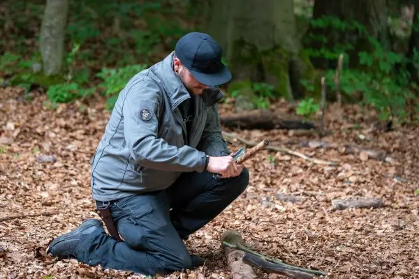 Messer bearbeitet Holzstück auf dem Waldboden