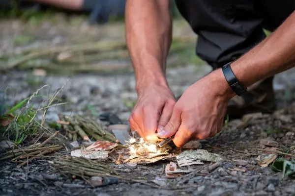 Person erzeugt Funken auf einem kleinen Holzstapel