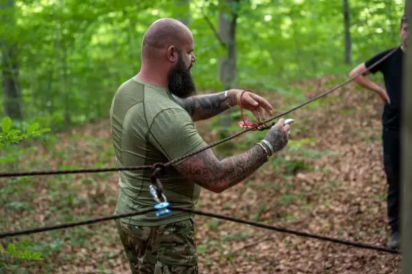 Person justiert eine Seilbrücke im Wald beim Survival Training