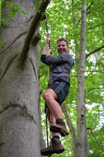 Person klettert an einem Seil einen Baum hoch