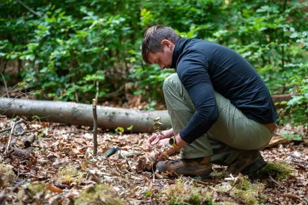 Person kniet im Wald und bearbeitet den Boden