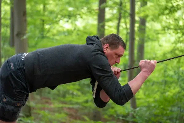 Person zieht an einem Seil im Wald