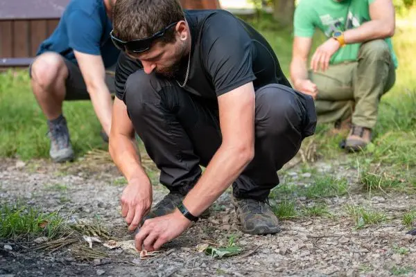 Person zündet mit Zunder ein Feuer an beim Survival Training