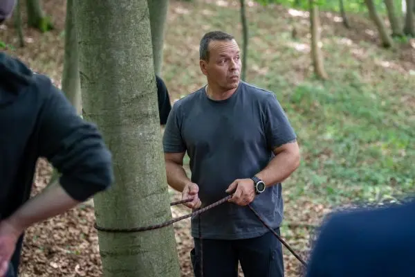 Seil wird um einen Baumstamm gewickelt, während eine Person beobachtet