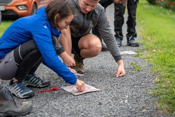 Zwei Personen analysieren eine Karte auf einem Kiesweg