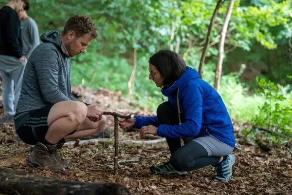 Zwei Personen konstruieren eine Holzkonstruktion aus Ästen im Wald