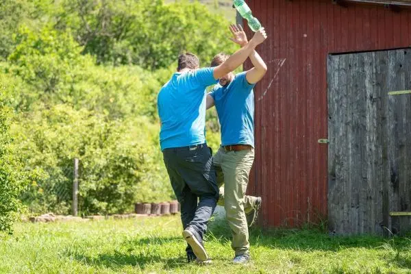 Zwei Personen tanzen auf einer Wiese vor einer roten Scheune