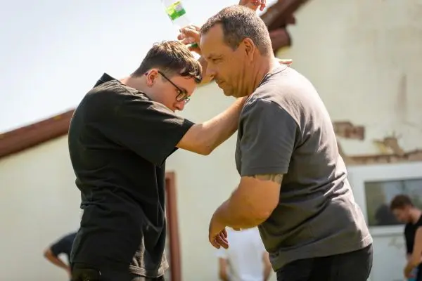 Zwei Personen üben eine Technik zur Selbstverteidigung im Freien