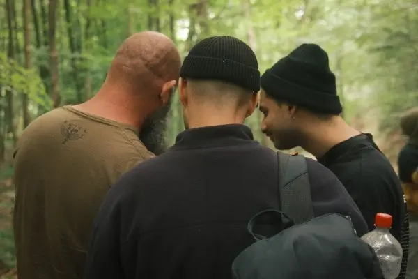Drei Personen betrachten gemeinsam ein Objekt im Wald