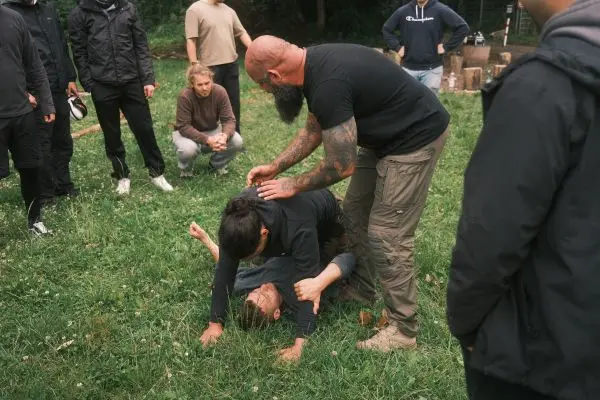 Ein Trainer demonstriert eine Technik zur Kontrolle eines Gegners auf einer Wiese