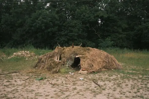 Eine selbstgebaute Hütte aus Gras und Ästen im Freien
