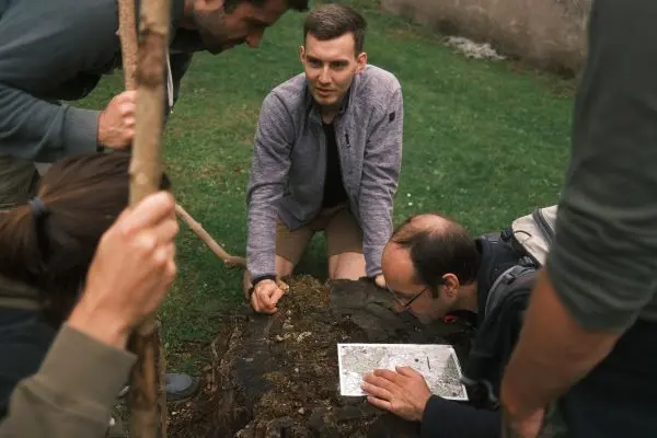 Gruppe betrachtet eine Karte auf einem Baumstumpf beim Überlebenstraining