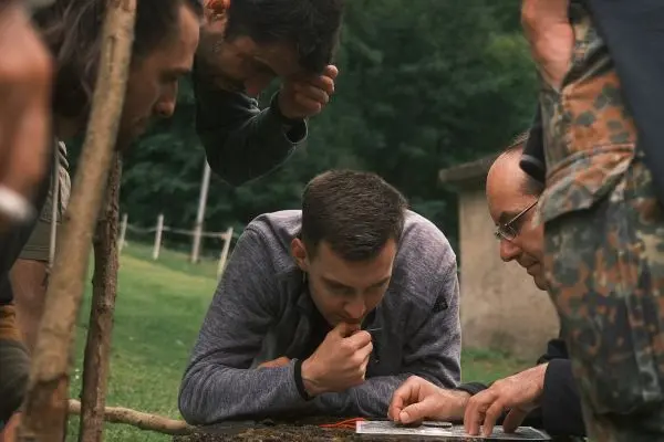 Gruppe von Personen betrachtet gemeinsam eine Karte auf dem Boden beim Überlebenstraining