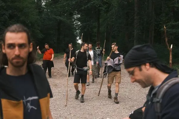 Gruppe von Personen mit Stöcken wandert auf einem Schotterweg durch den Wald