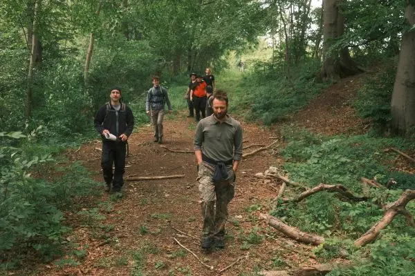 Gruppe wandert auf einem Waldweg zwischen Bäumen und Sträuchern