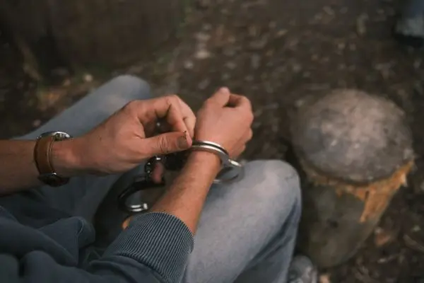 Hände legen Handfesseln an einem Handgelenk an