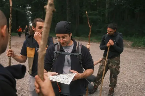 Kartenleser hält eine Karte, während andere Teilnehmer mit Stöcken stehen