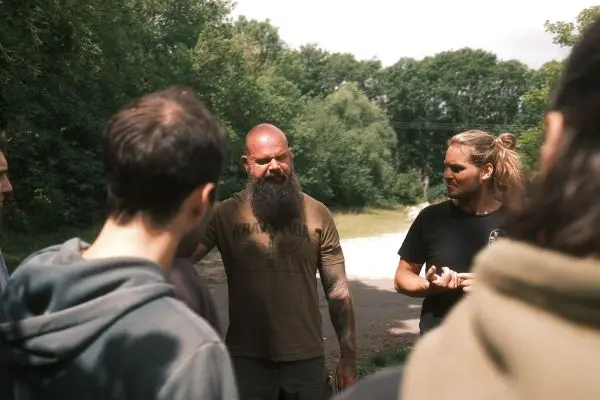 Mann mit Bart erklärt einer Gruppe im Freien eine Technik oder Strategie