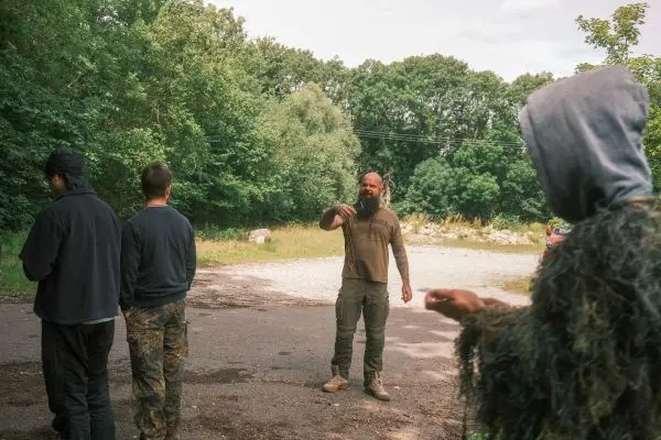 Mann mit Bart erklärt einer Gruppe im Waldgebiet eine Technik
