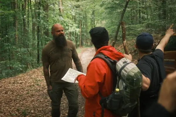 Person zeigt auf Karte, während andere Person zuhört im Wald
