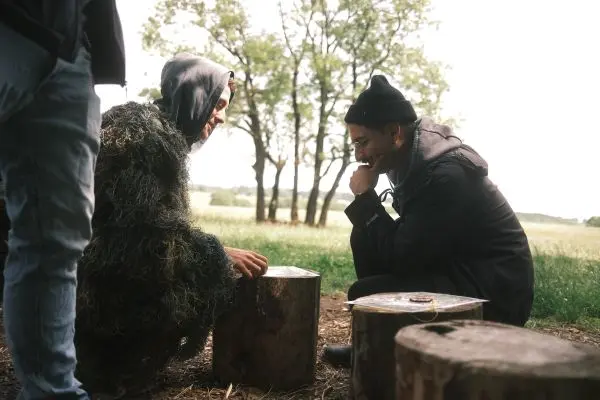 Zwei Personen sitzen auf Baumstümpfen und betrachten eine Holzoberfläche