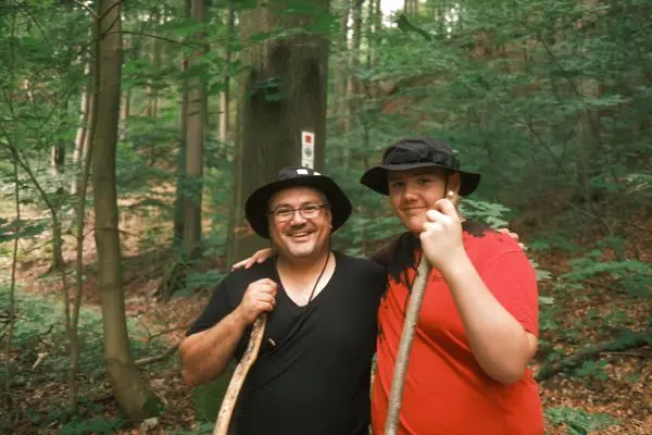 Zwei Personen stehen im Wald und halten Wanderstöcke
