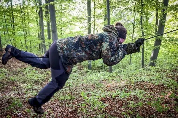 Person nutzt eine selbstgebaute Seilbrücke zur Fortbewegung im Wald