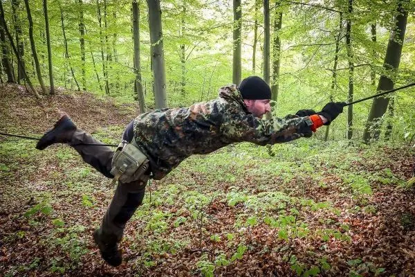 Person nutzt Seilbrücke zur Fortbewegung über den Waldboden