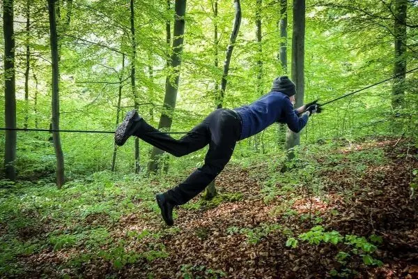 Person nutzt selbstgebaute Seilbrücke zur Fortbewegung im Wald