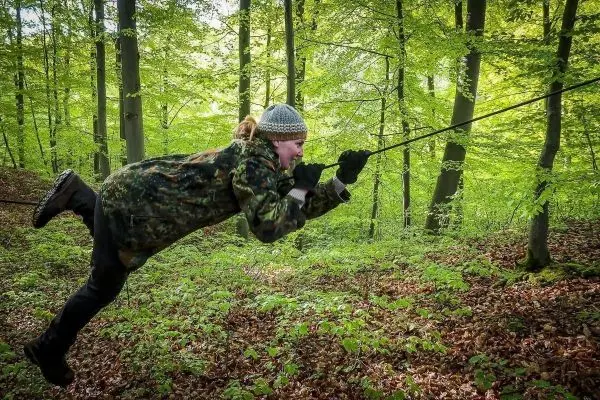 Person schwingt an einem Seil durch den Wald
