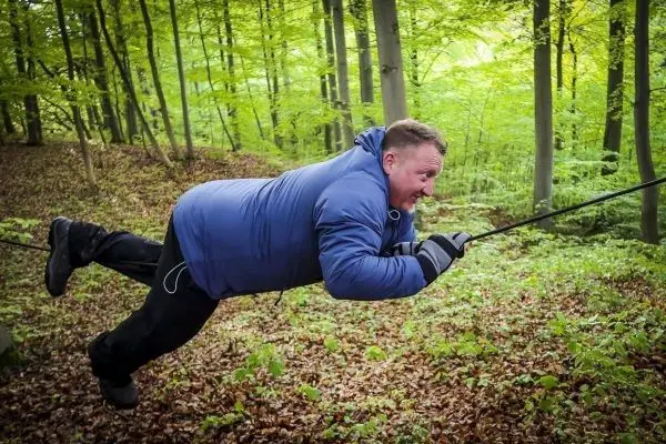 Person schwingt an einem Seil durch den Wald