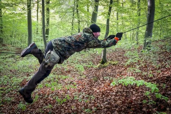 Person schwingt an einem Seil durch den Wald
