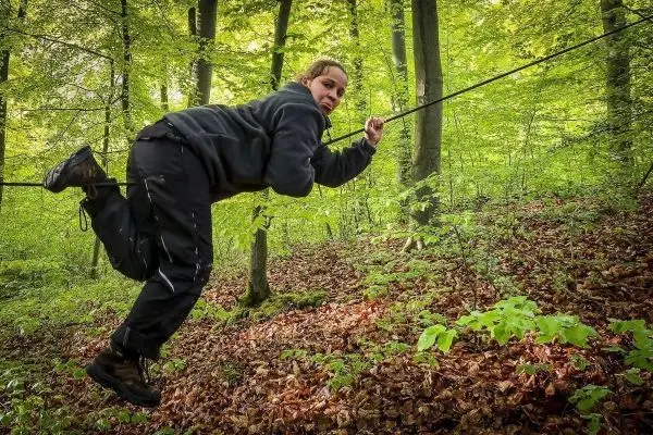 Person schwingt an einem Seil durch den Wald beim Überlebenstraining