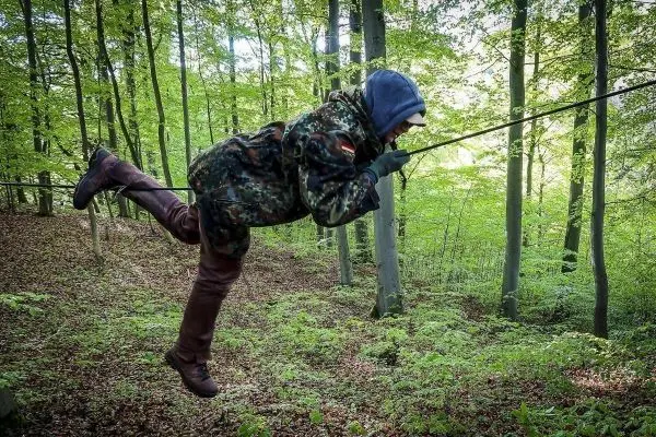 Person schwingt an einer Seilbrücke durch den Wald