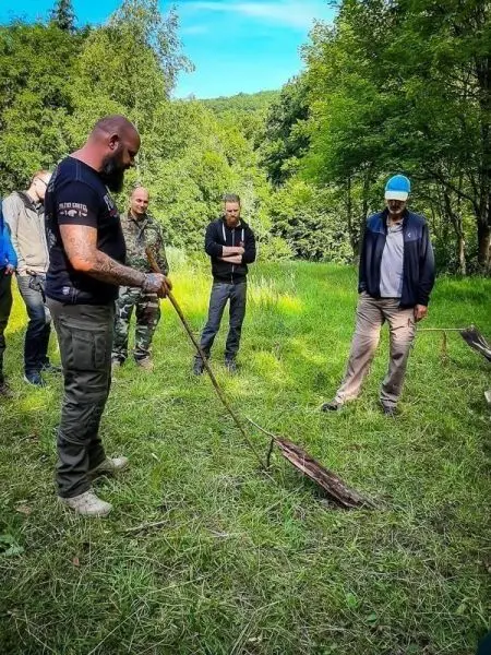 Ein Mann demonstriert eine einfache Schlagfalle mit einem Stock auf dem Boden