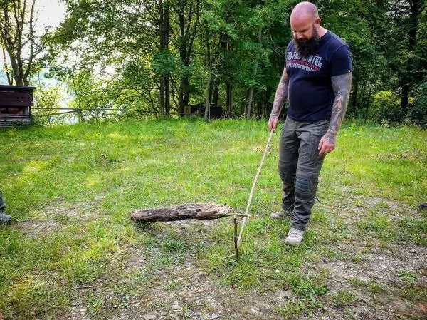Ein Mann positioniert einen Stock für eine einfache Schlagfalle im Gras