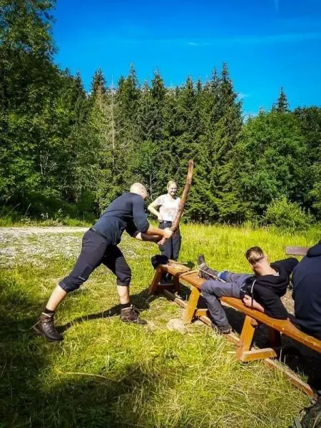 Ein Mann spaltet Holz mit einer Axt auf einer Holzbank im Freien