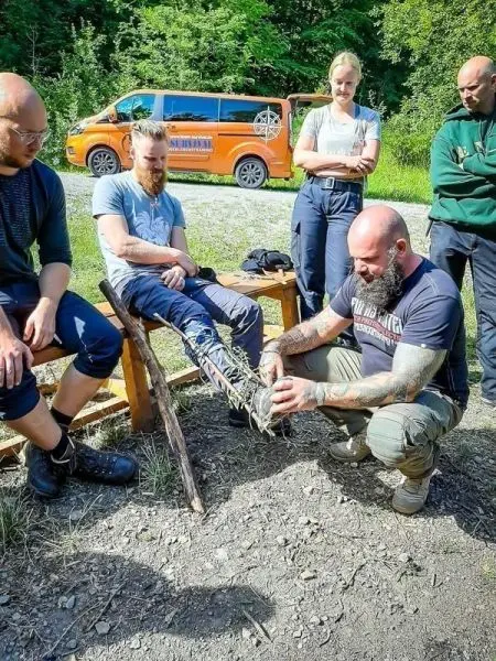 Ein Teilnehmer bindet eine improvisierte Schiene an das Bein eines anderen