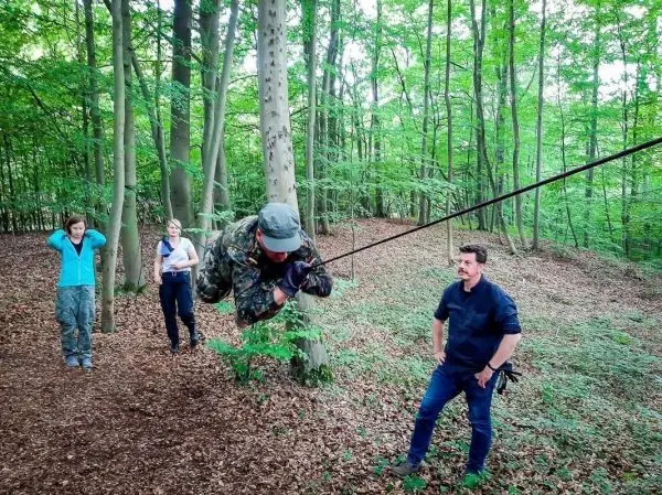 Ein Teilnehmer nutzt eine Seilbrücke, um sich zwischen Bäumen fortzubewegen