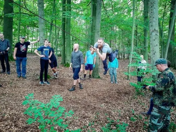 Ein Teilnehmer schwingt an einer selbstgebauten Seilbrücke zwischen Bäumen