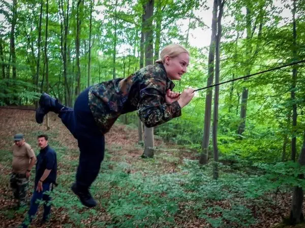 Eine Person schwingt an einem Seil zwischen Bäumen im Wald