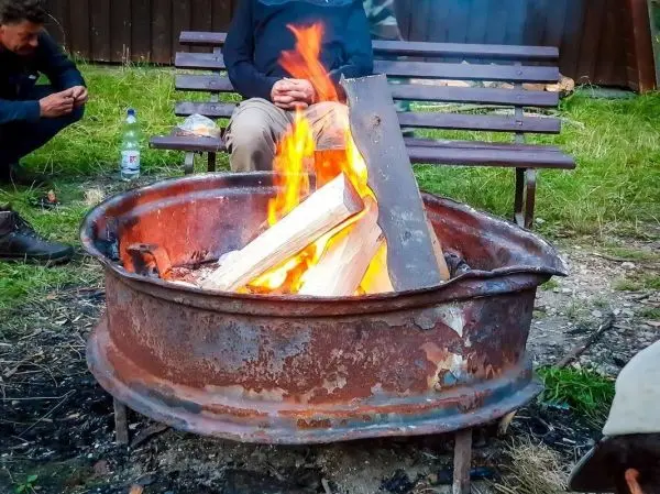 Feuer brennt in einem rostigen Metallfeuerkorb mit Holzscheiten