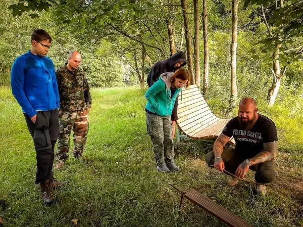 Gruppe beobachtet Anleitung zur Herstellung einer improvisierten Trage im Wald