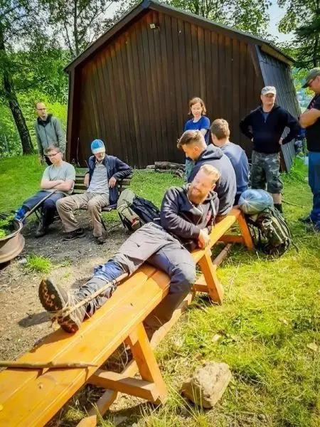 Gruppe sitzt auf Bänken und unterhält sich in der Nähe einer Holzhütte