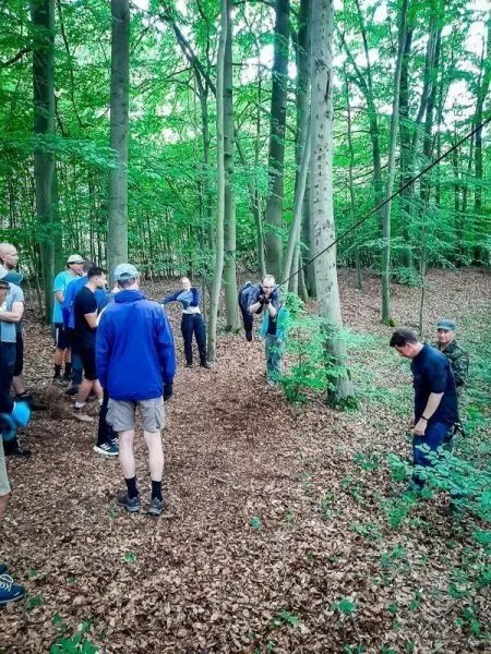 Gruppe übt den Aufbau einer selbstgebauten Seilbrücke zwischen Bäumen im Wald