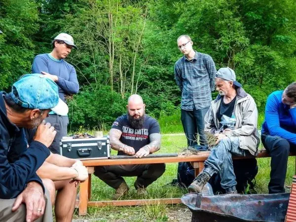 Gruppe von Personen beobachtet Anleitung zum Feuer machen am Tisch beim Survival Training